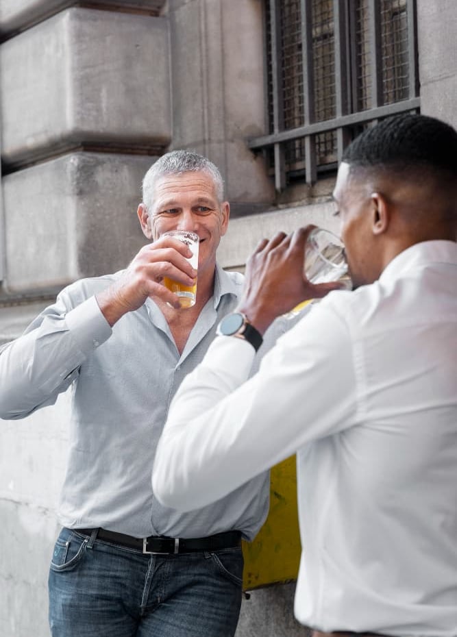 gay sugar daddy and sugar baby are drinking beer and networking outside a city pub.
