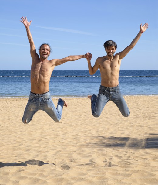two man jumping above brown beach sand