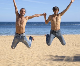 two man jumping above brown beach sand