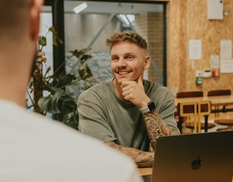 A man smiles while talking to someone.