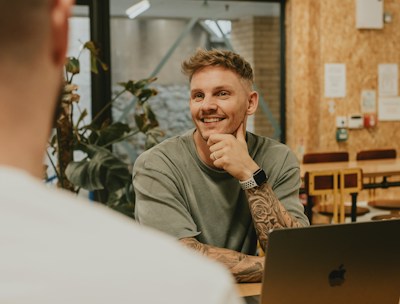 A man smiles while talking to someone.